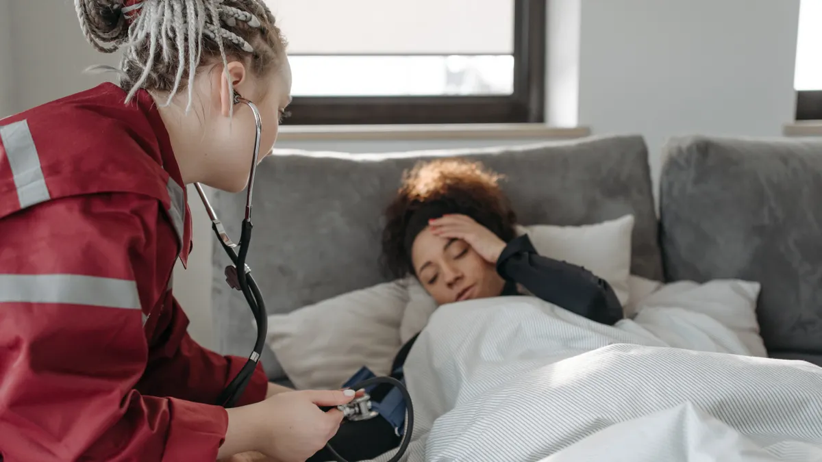 Nurse taking blood pressure of a bedridden patient