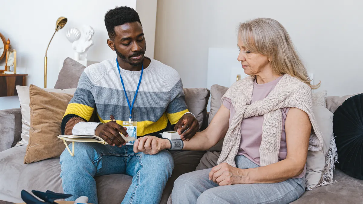Care at home roles and services — The Complete Guide Care worker checking an older woman's wrist blood pressure