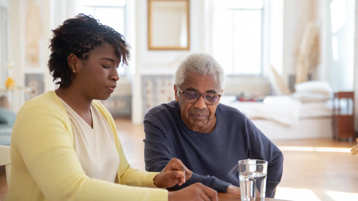 Care at home roles and services — The Complete Guide Caregiver helping an older man at a table
