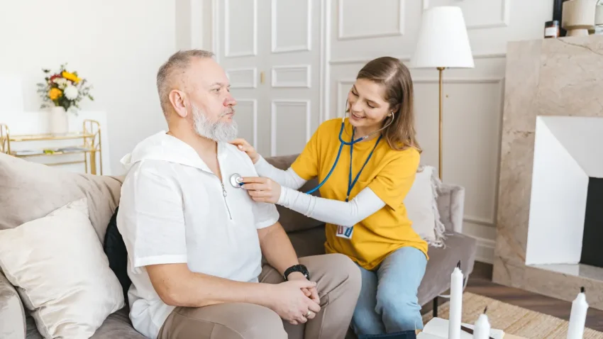 Home care worker checking an older man with a stethoscope